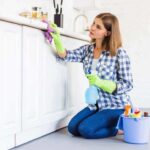 A woman from housekeeping services is cleaning the shelf